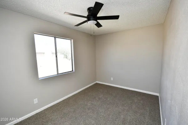 an empty room with a window and a ceiling fan