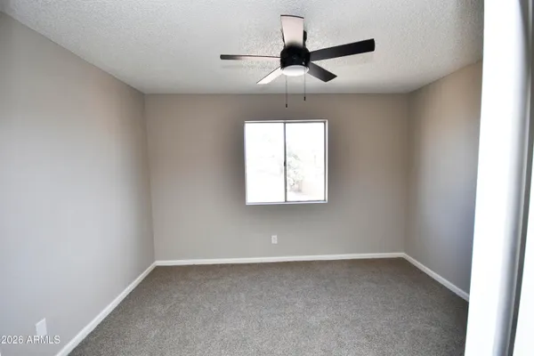 an empty room with a window and a fan