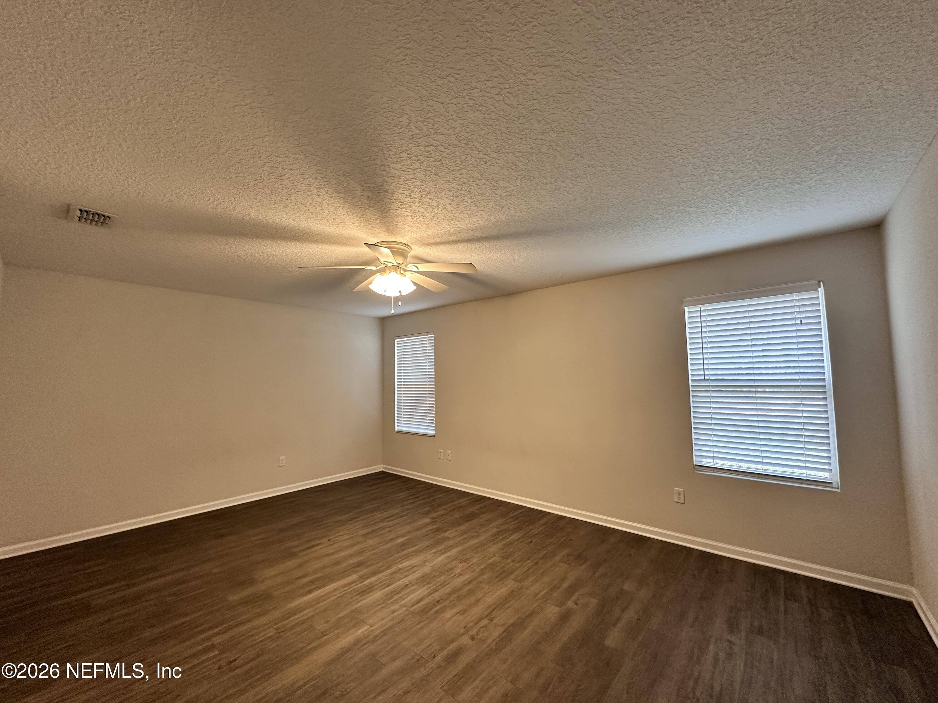 3460 Belfort Road Jacksonville, FL 32216 - Photo 8 of 16 an empty room with wooden floor fan and windows