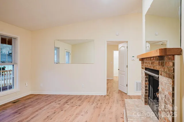 a view of empty room with wooden floor and fireplace
