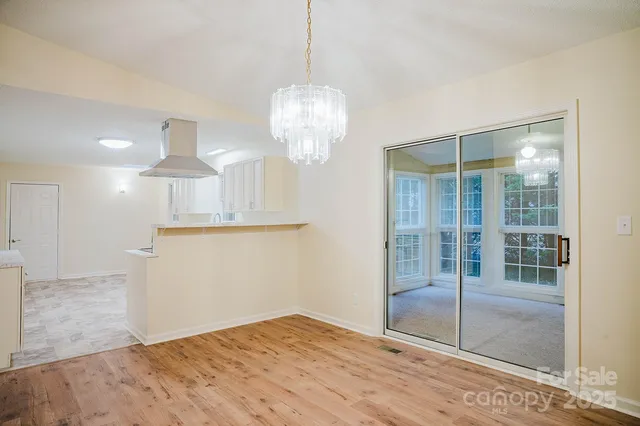 a view of a hallway with wooden floor and chandelier