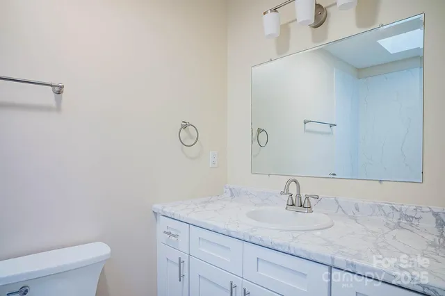 a bathroom with a granite countertop sink a toilet and a mirror