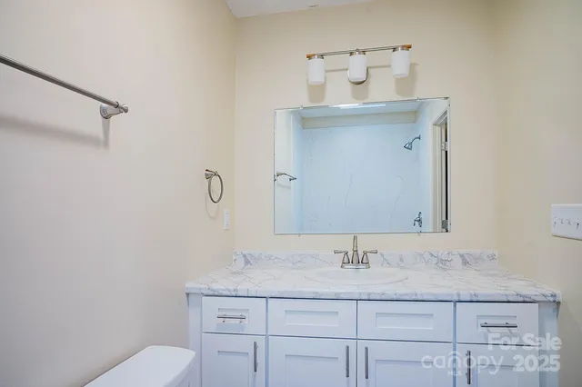a bathroom with a granite countertop sink a toilet and a mirror