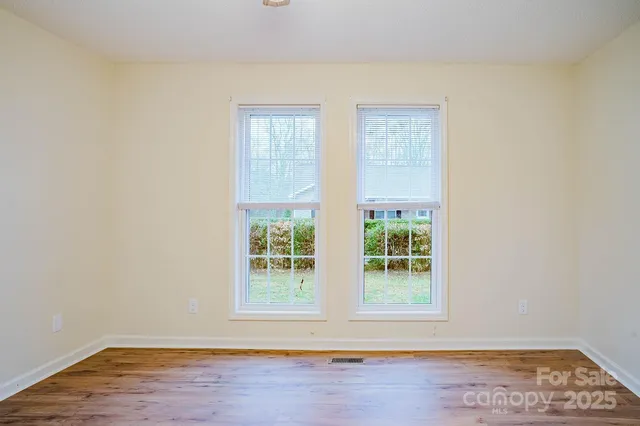 an empty room with wooden floor fan and windows