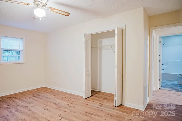 an empty room with wooden floor fan and windows