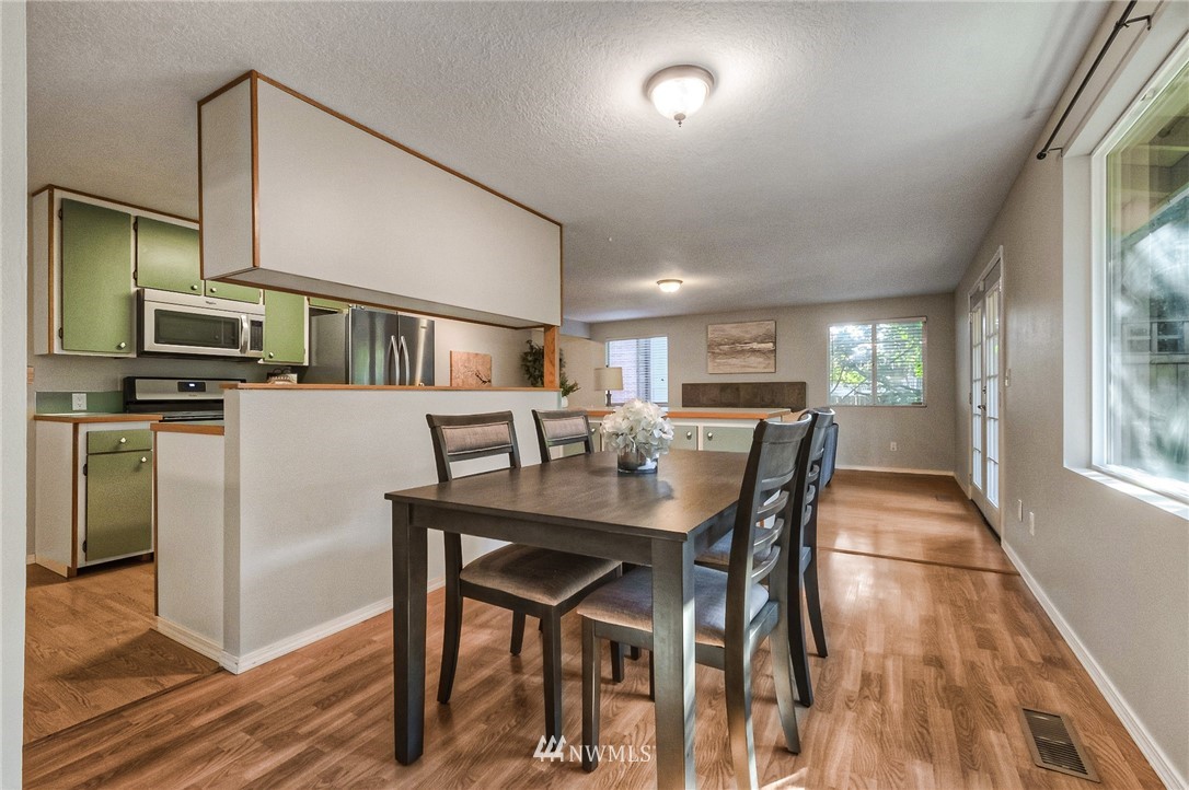 13708 Southeast 141st Street Renton, WA 98059 - Photo 7 of 19 a kitchen with stainless steel appliances a dining table chairs stove refrigerator and microwave