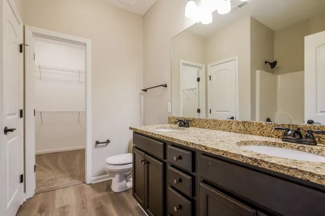 a bathroom with a granite countertop sink a toilet and a mirror
