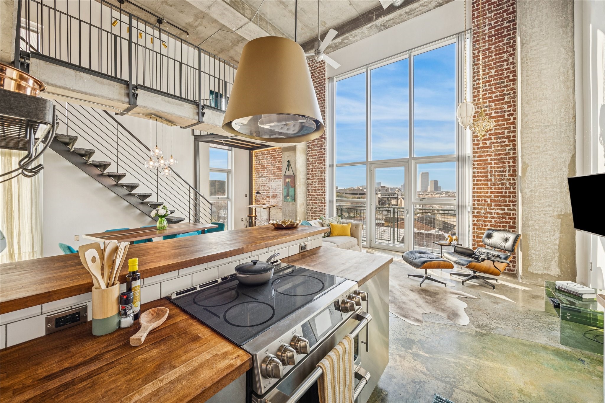From the kitchen sink, enjoy an open view into the living room showcasing the home’s seamless layout, featuring a European floating ductless vent hood. Cafe stove with conventional double ovens.