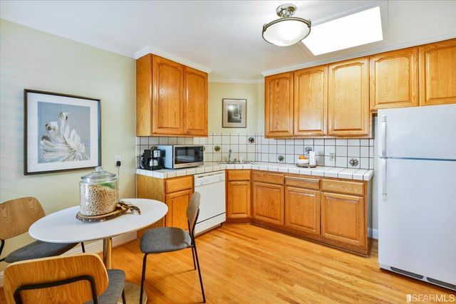 a kitchen with stainless steel appliances granite countertop a sink a stove a dining table and chairs