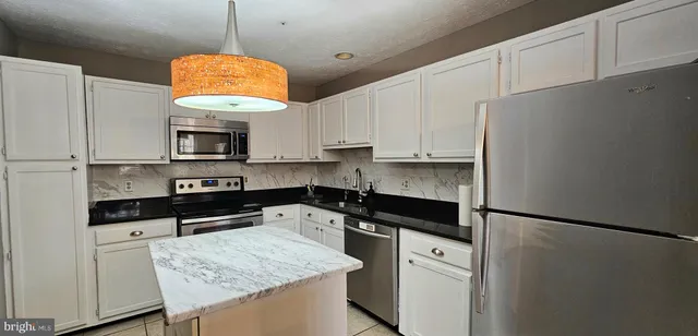 a kitchen with granite countertop a sink a center island stainless steel appliances and cabinets