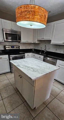 a kitchen with kitchen island granite countertop a sink and a stove