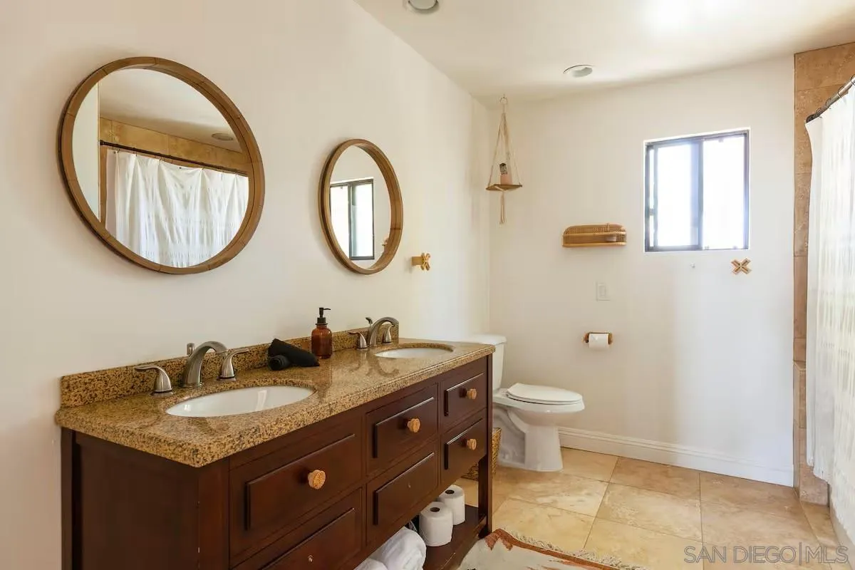 837 4th Street Encinitas, CA 92024 - Photo 29 of 41 a bathroom with a granite countertop toilet a sink and a mirror