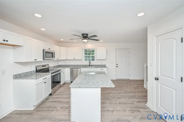 a large kitchen with cabinets countertop a sink a counter top space stainless steel appliances and a window