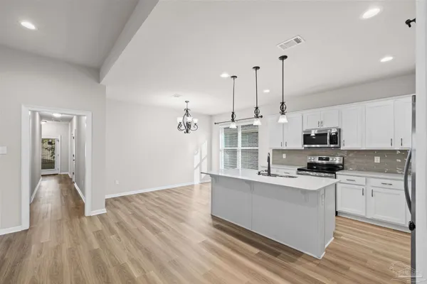 a kitchen with stainless steel appliances kitchen island a sink a refrigerator and chairs