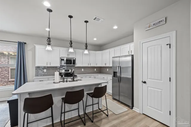 a kitchen with stainless steel appliances kitchen island granite countertop a dining table chairs and white cabinets
