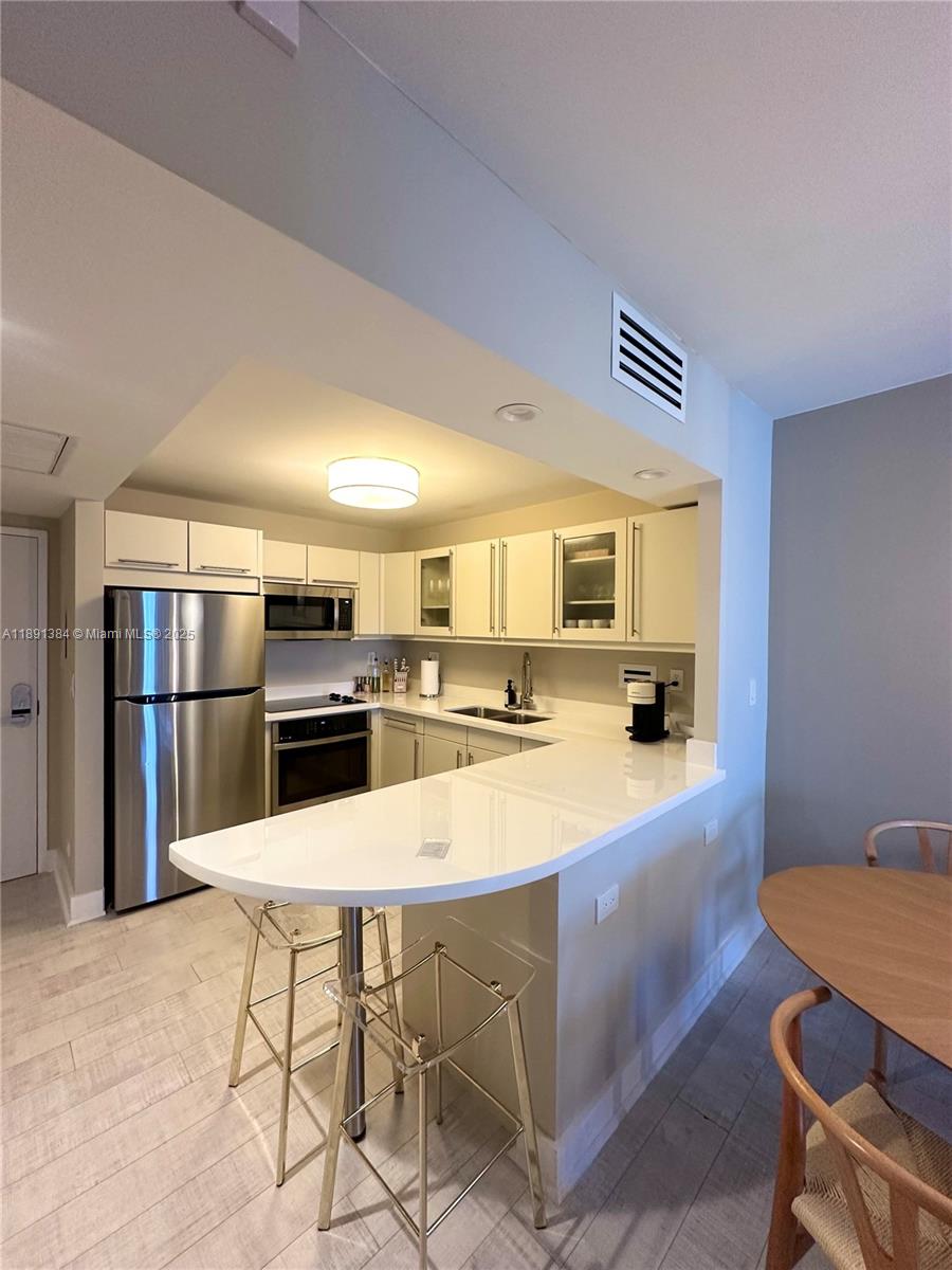 2301 Collins Avenue, Unit 836 Miami Beach, FL 33139 - Photo 5 of 29 a kitchen with stainless steel appliances kitchen island granite countertop a table chairs and a refrigerator