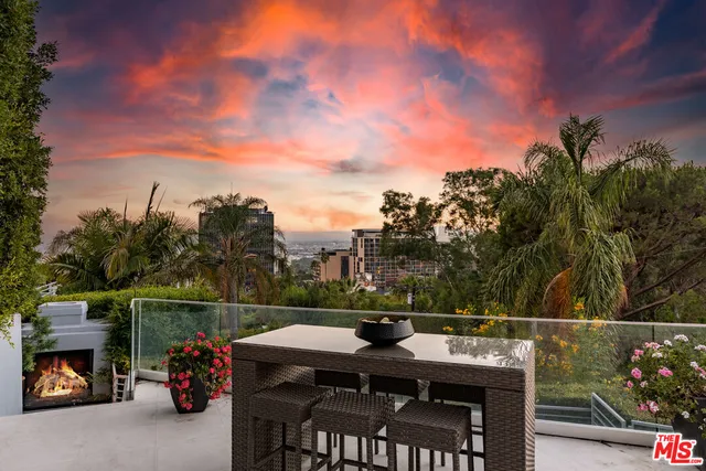 a backyard of a house with table and chairs under an umbrella