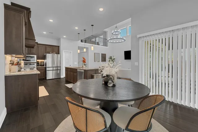 a kitchen with stainless steel appliances a dining table chairs and couches with wooden floor