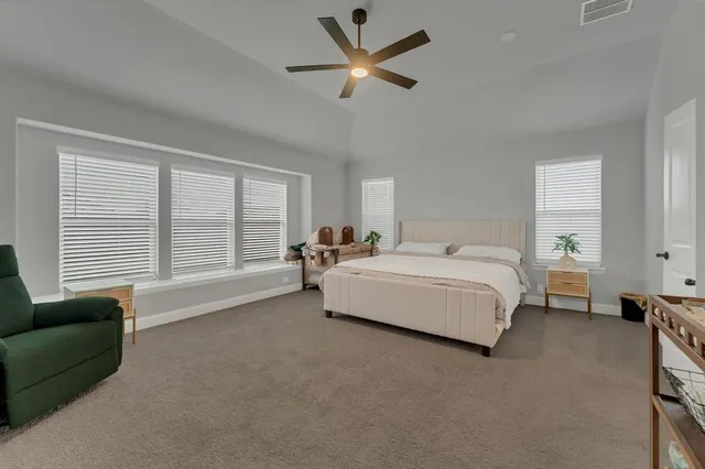 a spacious bedroom with a bed a couch and a chandelier