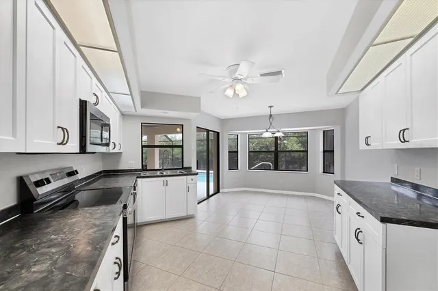 a large white kitchen with granite countertop a stove top oven a sink and dishwasher