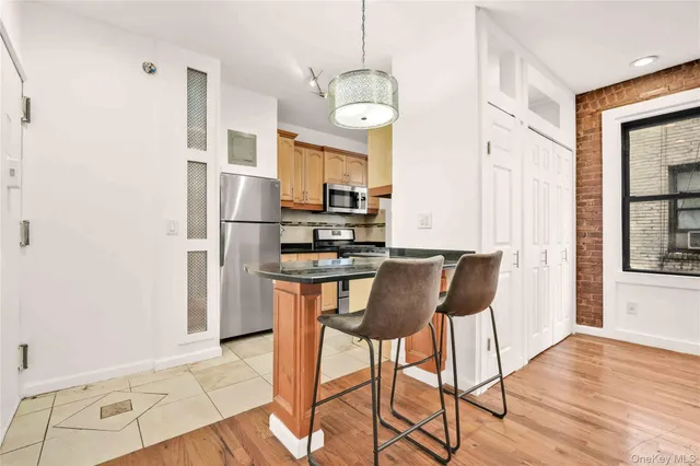 a kitchen with stainless steel appliances granite countertop a refrigerator a stove a microwave oven a dining table and chairs with wooden floor