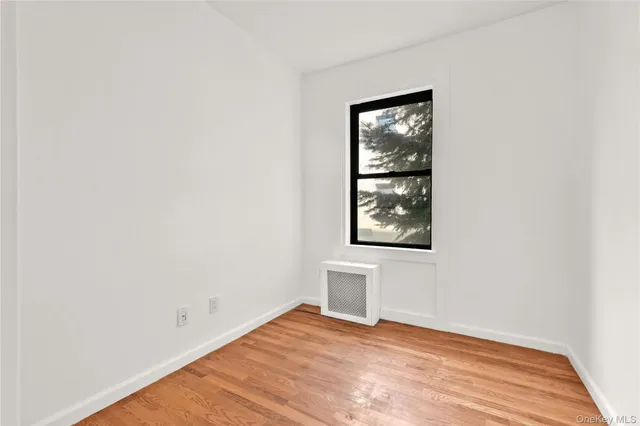 a view of an empty room with window and wooden floor
