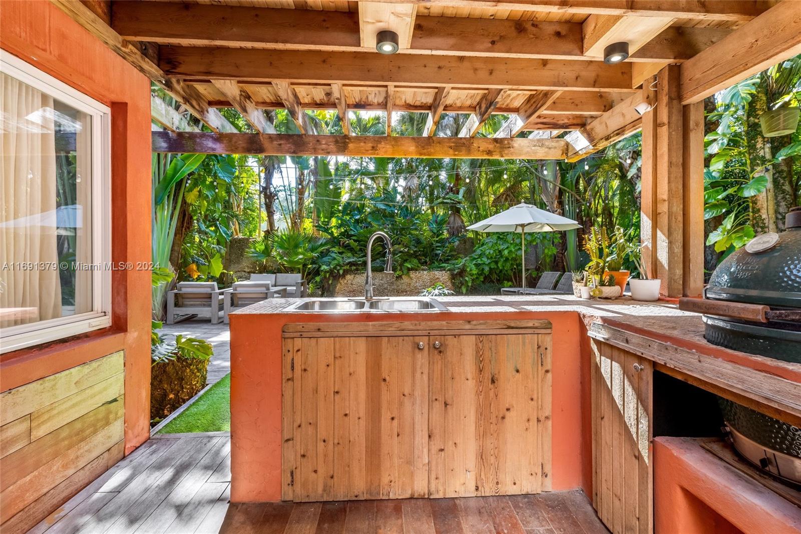 3685 St Gaudens Road Miami, FL 33133 - Photo 48 of 66 a kitchen with a wooden floor a yard a table and chairs under an umbrella