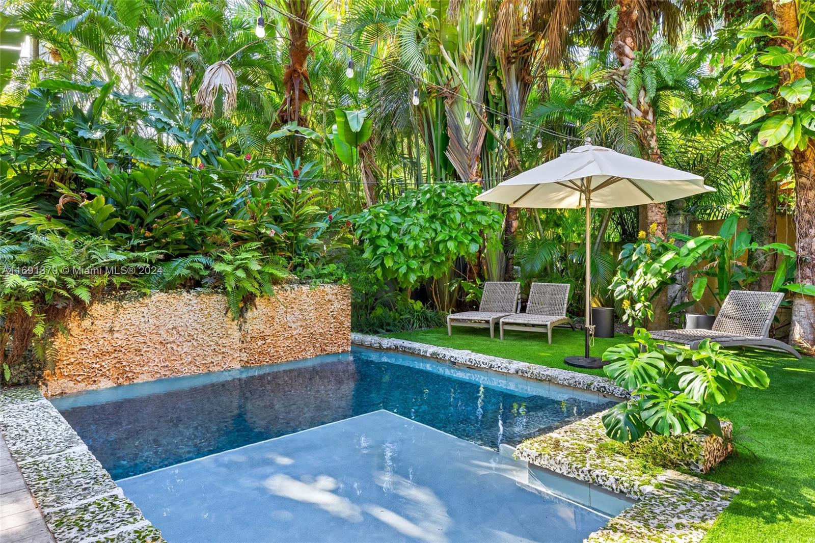 3685 St Gaudens Road Miami, FL 33133 - Photo 53 of 66 a view of a backyard with chairs under an umbrella