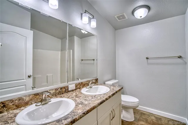 a bathroom with a granite countertop sink toilet and a mirror