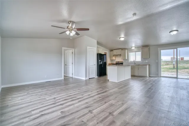 an empty room with wooden floor and a kitchen