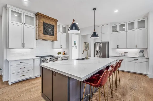 a open kitchen with stainless steel appliances granite countertop a stove a sink a refrigerator a dining table and chairs with wooden floor