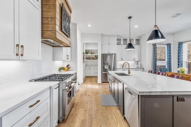 a kitchen with stainless steel appliances granite countertop a sink a stove and a wooden floors