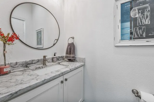 a bathroom with a granite countertop sink and a mirror