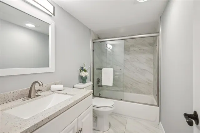 a bathroom with a granite countertop sink a toilet and shower