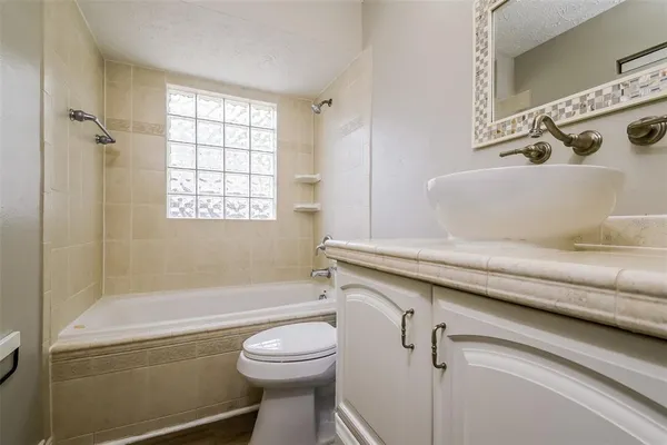 a bathroom with a granite countertop bathtub sink vanity mirror and toilet