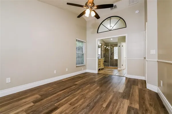 a view of empty room with wooden floor and fan
