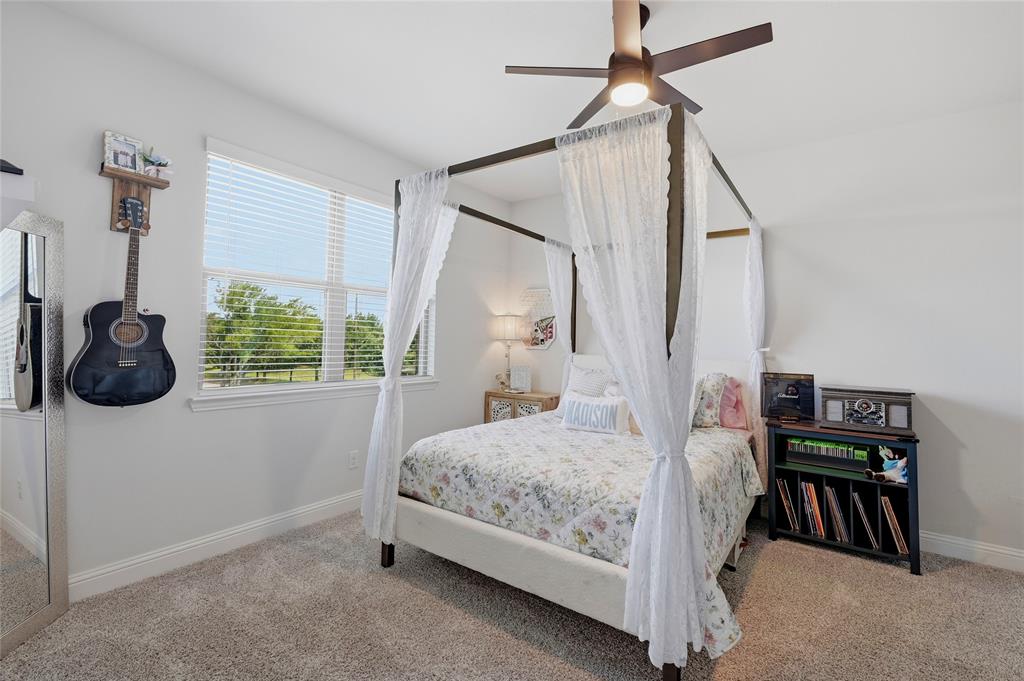 864 Shadow Valley Road Whitesboro, TX 76273 - Photo 38 of 40 Bedroom featuring light gray walls, plush carpet flooring, a large window with blinds, a dark-toned ceiling fan with integrated lighting, and white trim throughout