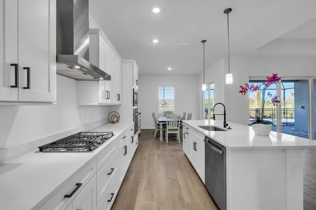 a kitchen with stainless steel appliances a stove a chimney a sink and cabinets