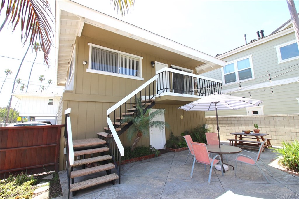 a view of a patio with a table and chairs under an umbrella with a small yard