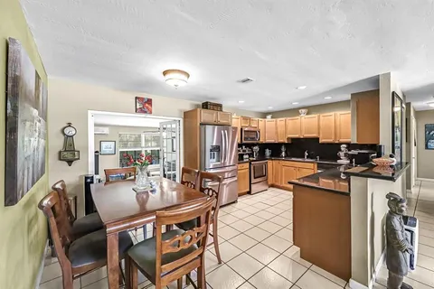 a dining room with stainless steel appliances kitchen island granite countertop a sink and chairs