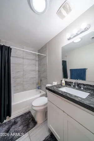 a bathroom with a granite countertop sink toilet a mirror and bathtub