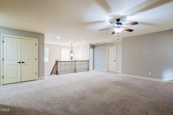 an empty room with chandelier fan and fireplace