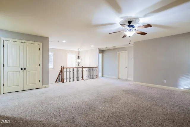an empty room with chandelier fan and fireplace
