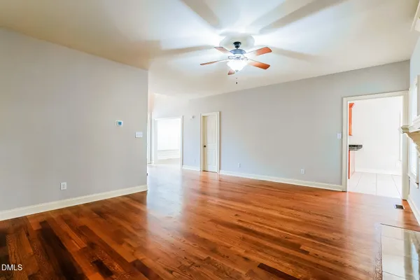 a view of an empty room with wooden floor fireplace and a window