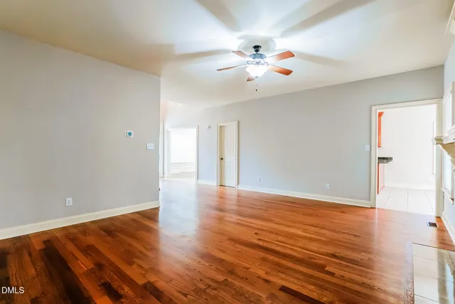 a view of an empty room with wooden floor fireplace and a window