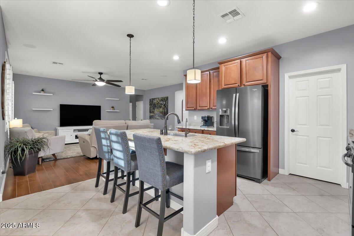 3214 North Springfield Street Buckeye, AZ 85396 - Photo 11 of 64 a kitchen with stainless steel appliances kitchen island granite countertop a refrigerator a stove a sink a dining table and chairs with wooden floor