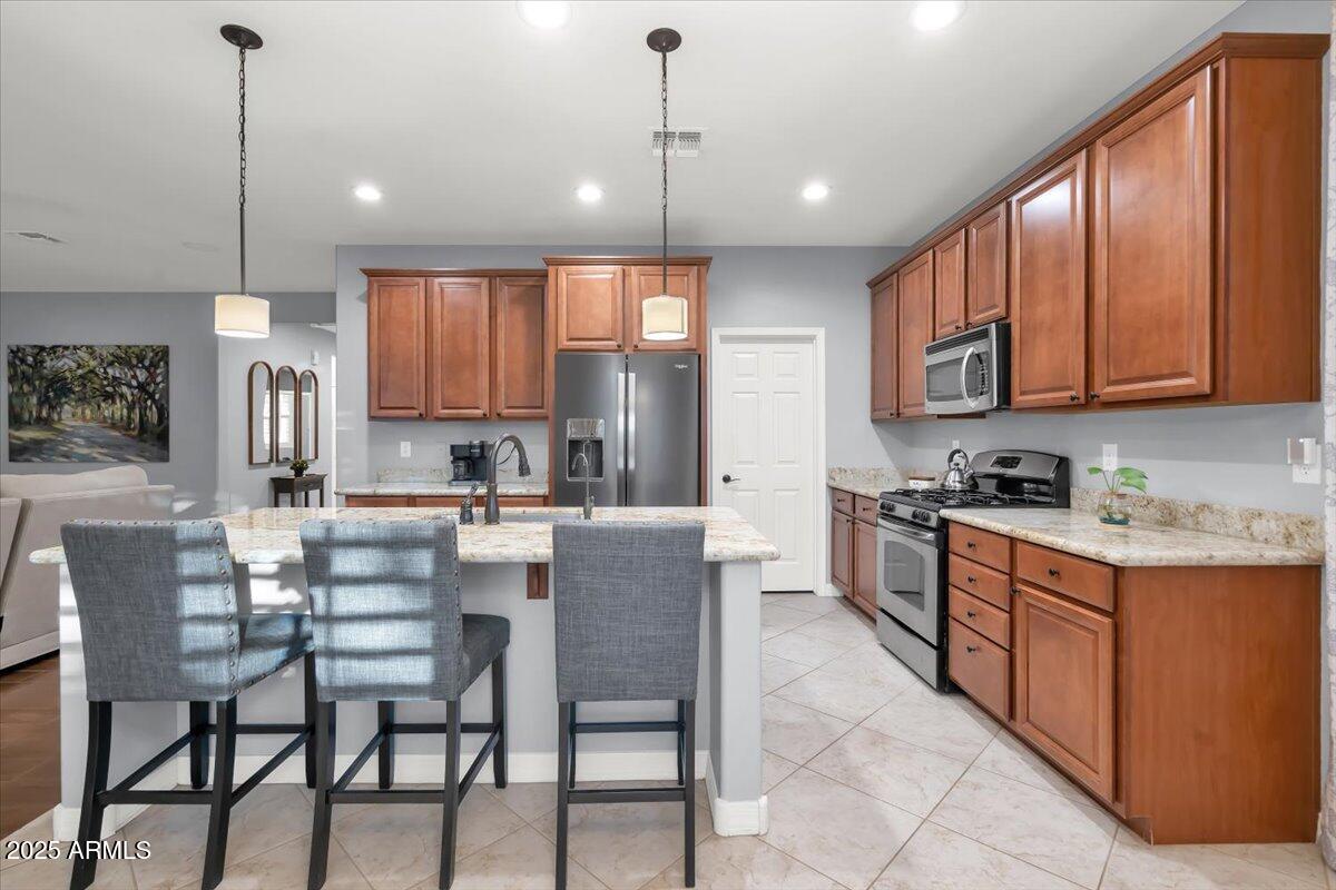 3214 North Springfield Street Buckeye, AZ 85396 - Photo 12 of 64 a kitchen with stainless steel appliances granite countertop a stove a sink a refrigerator a dining table and chairs with white cabinets