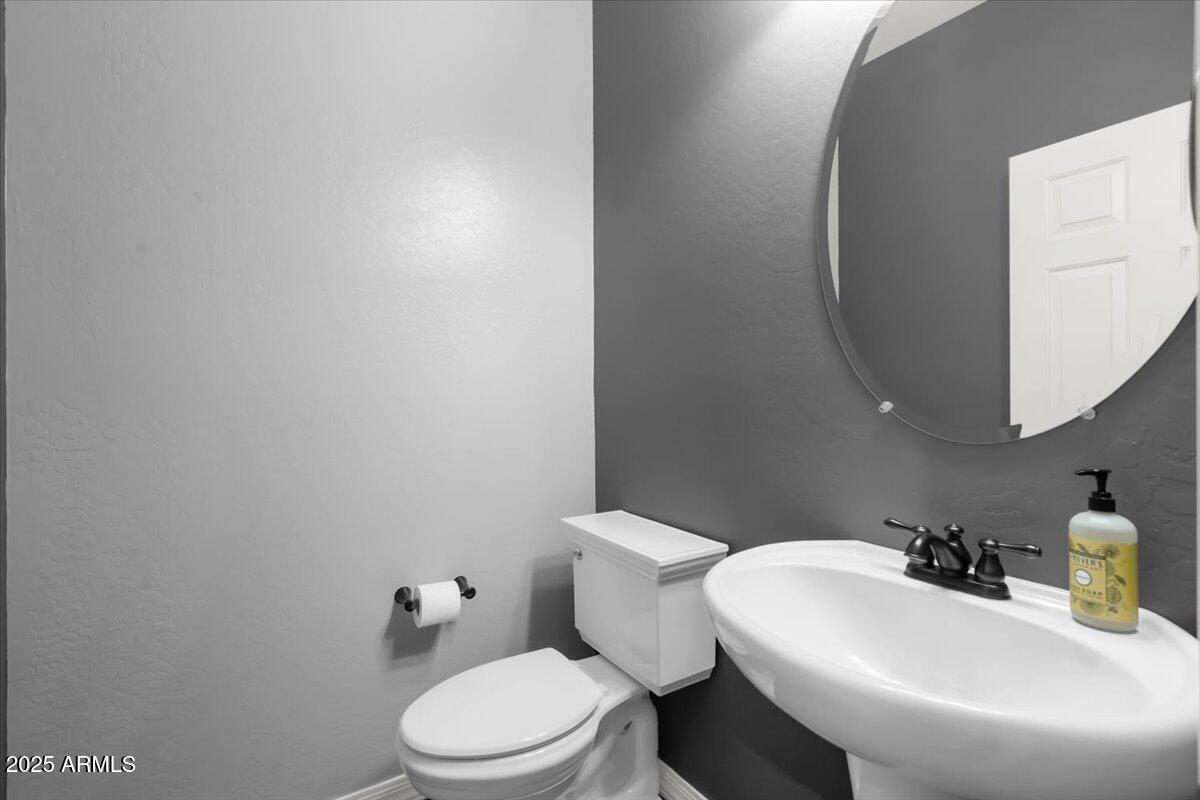 3214 North Springfield Street Buckeye, AZ 85396 - Photo 15 of 64 a white toilet sitting next to a bathroom sink