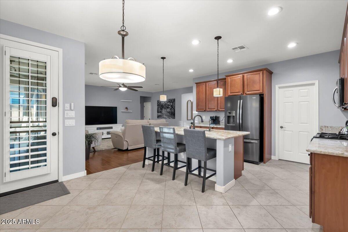 3214 North Springfield Street Buckeye, AZ 85396 - Photo 9 of 64 a kitchen with stainless steel appliances kitchen island granite countertop a sink and a refrigerator