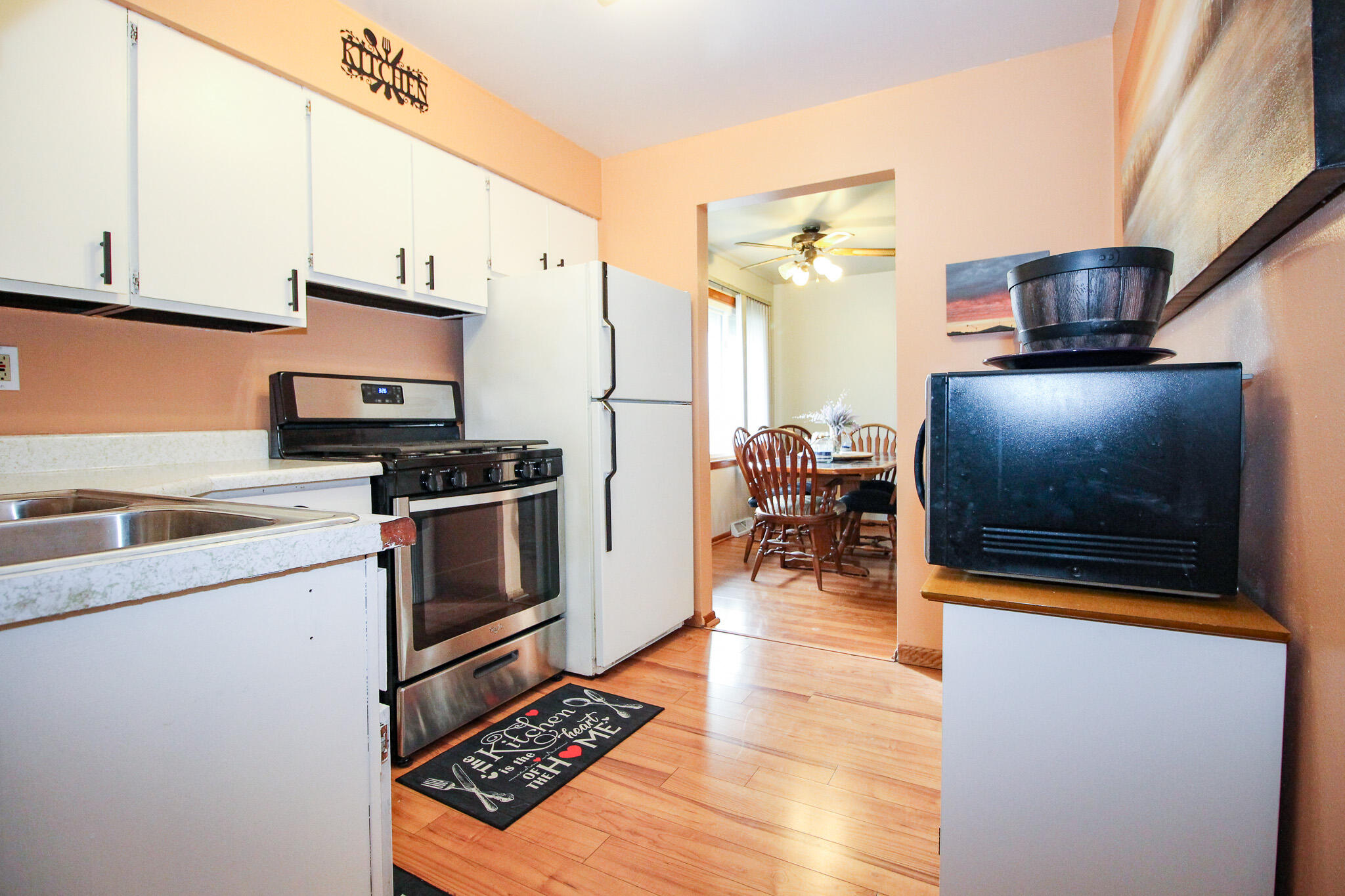 6912 Colorado Street Merrillville, IN 46410 - Photo 19 of 40 a kitchen with stainless steel appliances a stove a sink and white cabinets